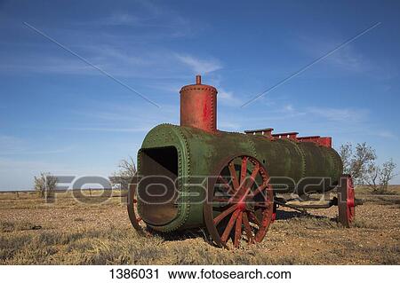Stock Image - Abandoned steam engine on field against blue sky. Fotosearch