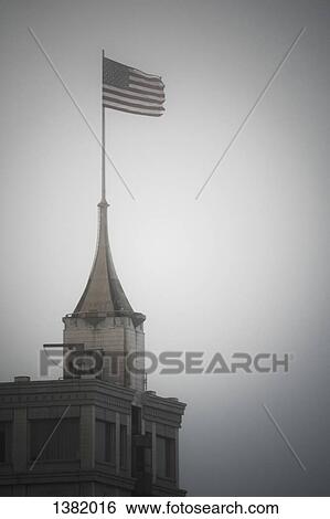 American flag on top of building against clear sky View Large Photo Image Stock Photograph - American flag on top of building against clear sky. Fotosearch