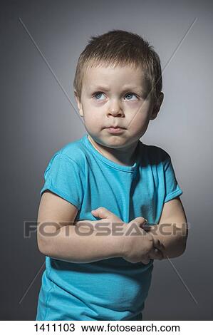 Angry boy looking away while standing arms crossed against gray background View Large Photo Image Stock Image - Angry boy looking away while standing arms crossed against gray background. Fotosearch