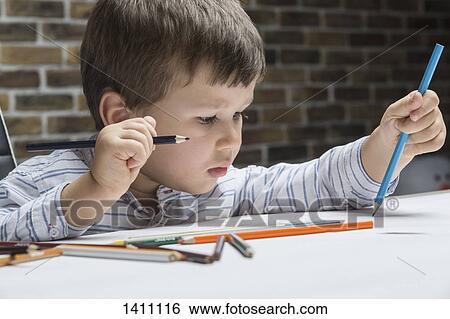 Boy drawing at table in house View Large Photo Image Stock Photograph - Boy drawing at table in house. Fotosearch
