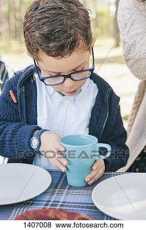 Boy holding coffee mug at table in forest View Large Photo Image Stock Photo - Boy holding coffee mug at table in forest. Fotosearch