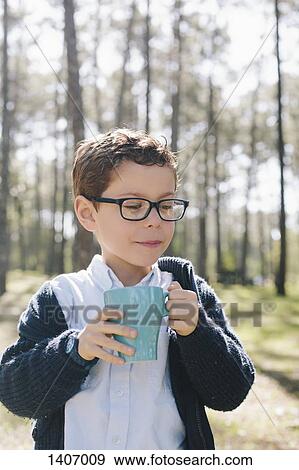 Stock Photo - Boy holding coffee mug in forest. Fotosearch