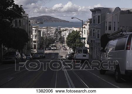 Stock Photograph - Cars parked on city street along buildings. Fotosearch