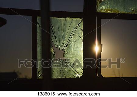 Stock Photography - Close-up of broken window of vehicle during sunset. Fotosearch