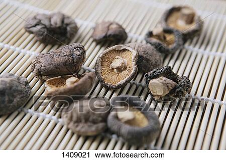 Stock Image - Close-up of dried mushrooms on bamboo mat. Fotosearch