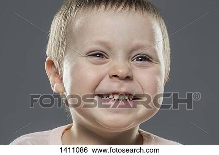 Stock Photograph - Close-up of happy boy against gray background. Fotosearch