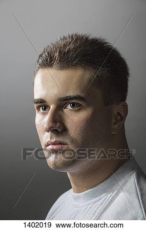Close-up of thoughtful young man against gray background View Large Photo Image Stock Photo - Close-up of thoughtful young man against gray background. Fotosearch