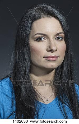 Stock Image - Close-up portrait of beautiful woman against gray background. Fotosearch