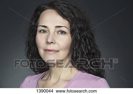 Picture - Close-up portrait of confident mature woman over gray background. Fotosearch