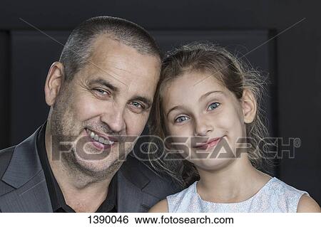 Stock Photograph - Close-up portrait of happy father with daughter over gray background. Fotosearch