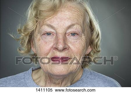 Stock Photography - Close-up portrait of smiling senior woman against gray background. Fotosearch