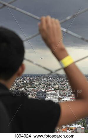 Cropped image of boys watching cityscape through chainlink fence View Large Photo Image Picture - Cropped image of boys watching cityscape through chainlink fence. Fotosearch