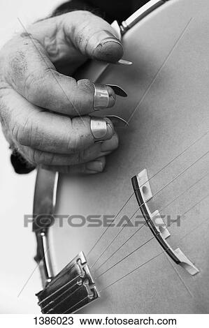 Stock Image - Cropped image of hand playing string instrument against gray background. Fotosearch