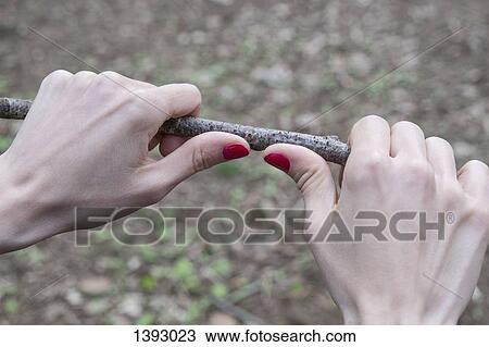 Stock Image - Cropped image of woman breaking stick. Fotosearch
