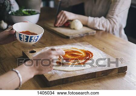 Cropped image of woman spreading tomato sauce over pizza dough View Large Photo Image Picture - Cropped image of woman spreading tomato sauce over pizza dough. Fotosearch