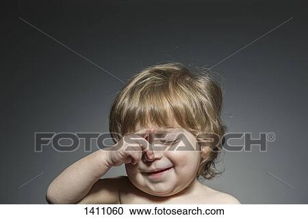 Stock Image - Cute boy rubbing eyes against gray background. Fotosearch