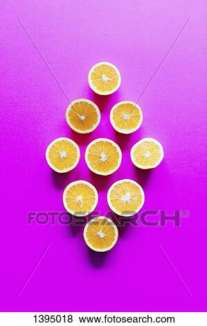 Stock Photo - Directly above shot of orange slices arranged in diamond shape on pink background. Fotosearch