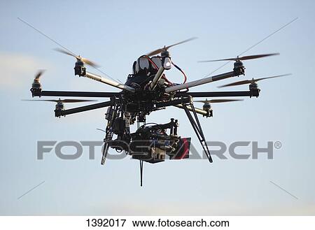 Drone with camera against sky View Large Photo Image Stock Photo - Drone with camera against sky. Fotosearch