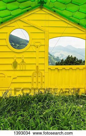 Picture - Exterior of yellow house with reflections of mountains on its windows. Fotosearch