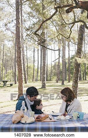Family sitting at breakfast table in forest View Large Photo Image Stock Photo - Family sitting at breakfast table in forest. Fotosearch