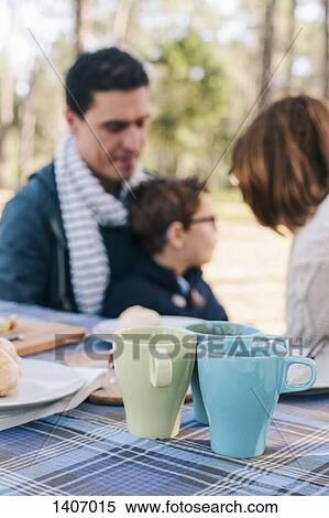 Stock Photography - Family sitting at breakfast table in forest. Fotosearch
