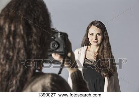 Female photographer photographing fashion model over gray background View Large Photo Image Stock Photo - Female photographer photographing fashion model over gray background. Fotosearch