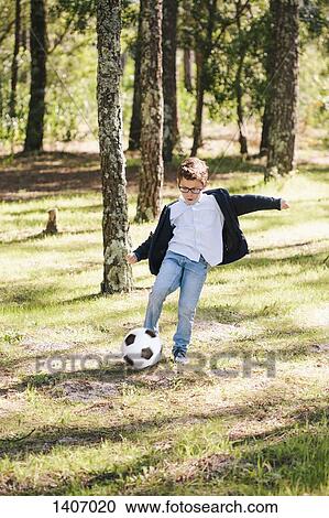 Full length of boy playing soccer in forest View Large Photo Image Stock Image - Full length of boy playing soccer in forest. Fotosearch
