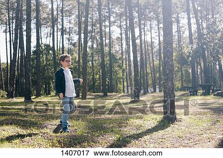 Stock Photo - Full length of boy walking in forest. Fotosearch