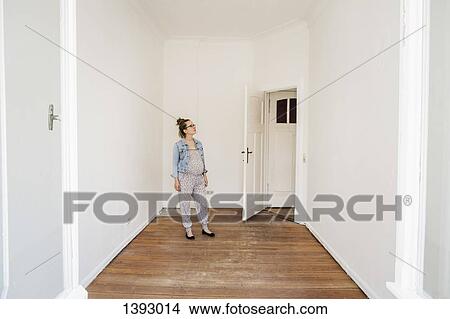 Picture - Full length of pregnant woman examining white wall of domestic room. Fotosearch