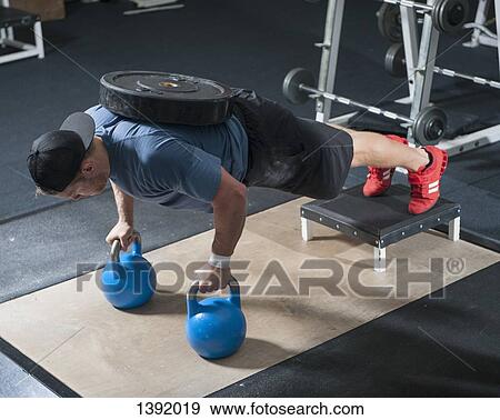 Full length of young man exercising in gym View Large Photo Image Stock Photo - Full length of young man exercising in gym. Fotosearch