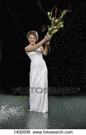 Full length portrait of smiling young bride holding bouquet while standing in water against black ba View Large Photo Image Stock Photograph - Full length portrait of smiling young bride holding bouquet while standing in water against black ba. Fotosearch