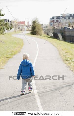 Stock Photo - Full length rear view of baby boy walking on road. Fotosearch