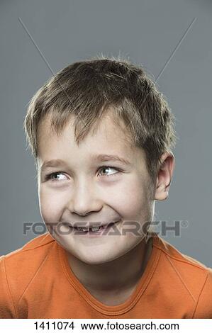 Happy boy looking away against gray background View Large Photo Image Picture - Happy boy looking away against gray background. Fotosearch