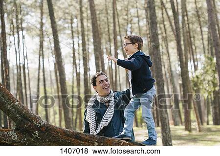 Happy father assisting son in climbing tree at forest View Large Photo Image Stock Photo - Happy father assisting son in climbing tree at forest. Fotosearch