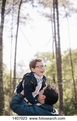 Happy man lifting boy in forest View Large Photo Image Stock Image - Happy man lifting boy in forest. Fotosearch