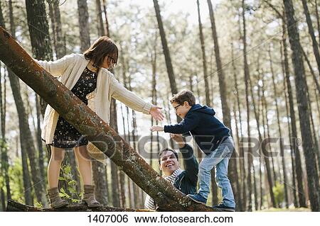 Happy parents assisting son in climbing tree at forest View Large Photo Image Stock Photograph - Happy parents assisting son in climbing tree at forest. Fotosearch