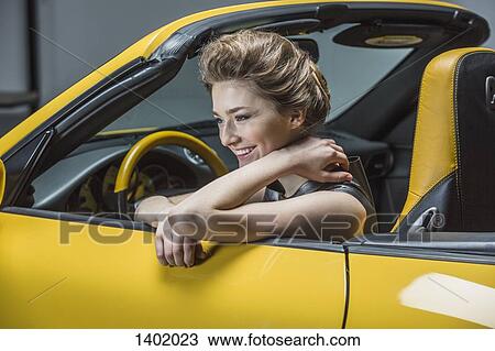 Happy woman looking away while sitting in convertible View Large Photo Image Stock Image - Happy woman looking away while sitting in convertible. Fotosearch