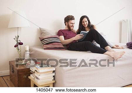 Happy young man reading book for woman in bed View Large Photo Image Stock Photo - Happy young man reading book for woman in bed. Fotosearch