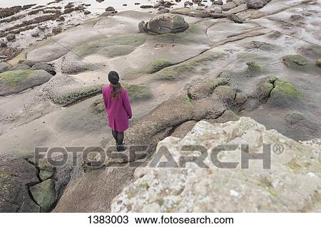 High angle rear view of woman standing on rocky shore View Large Photo Image Stock Image - High angle rear view of woman standing on rocky shore. Fotosearch