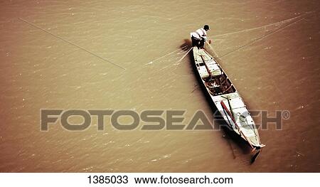 Stock Image - "High angle view of man fishing on Mekong river, Cambodia". Fotosearch