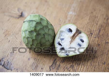 Stock Photo - High angle view of whole and halved cherimoya on wooden table. Fotosearch