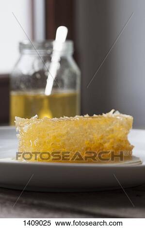 Honeycomb in plate by jar on table at home View Large Photo Image Stock Photography - Honeycomb in plate by jar on table at home. Fotosearch