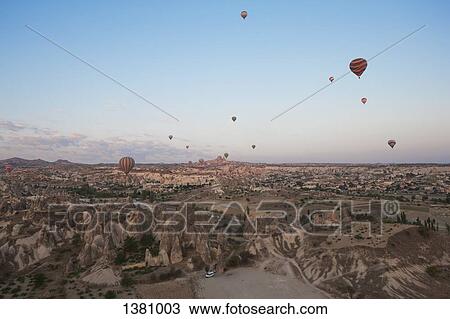 Stock Image - Hot air balloons flying over dramatic landscape. Fotosearch