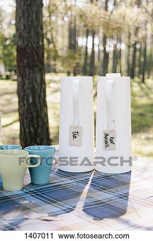 Stock Image - Jugs and mugs on table in forest. Fotosearch