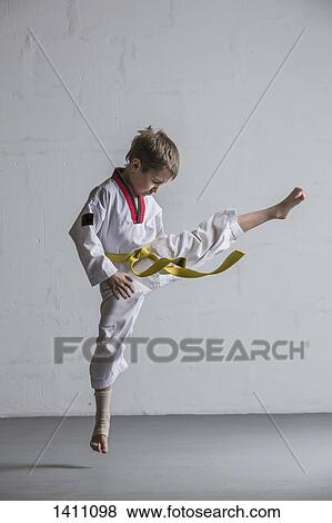 Karate boy kicking in air against white wall View Large Photo Image Stock Photo - Karate boy kicking in air against white wall. Fotosearch