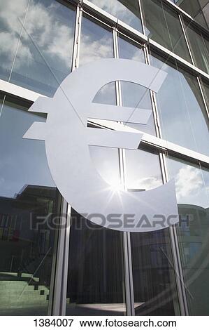 Stock Photo - Low angle view of euro symbol outside office building. Fotosearch