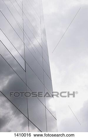 Stock Photograph - Low angle view of glass building against cloudy sky. Fotosearch