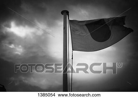 Picture - Low angle view of Japanese flag against cloudy sky. Fotosearch