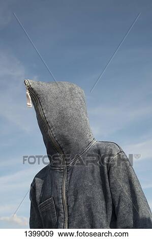 Stock Photo - Low angle view of person covered with hood against sky. Fotosearch
