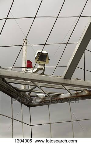 Stock Photography - Low angle view of surveillance camera attached on metal roof. Fotosearch